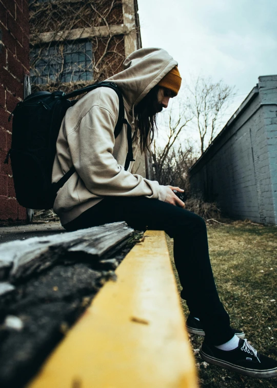 a man with long hair sitting on a ledge outside