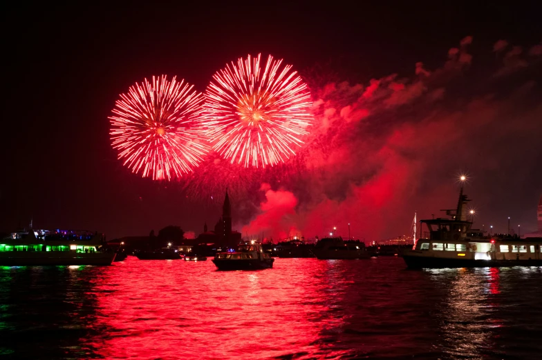 fireworks are lit up over a river in the night sky