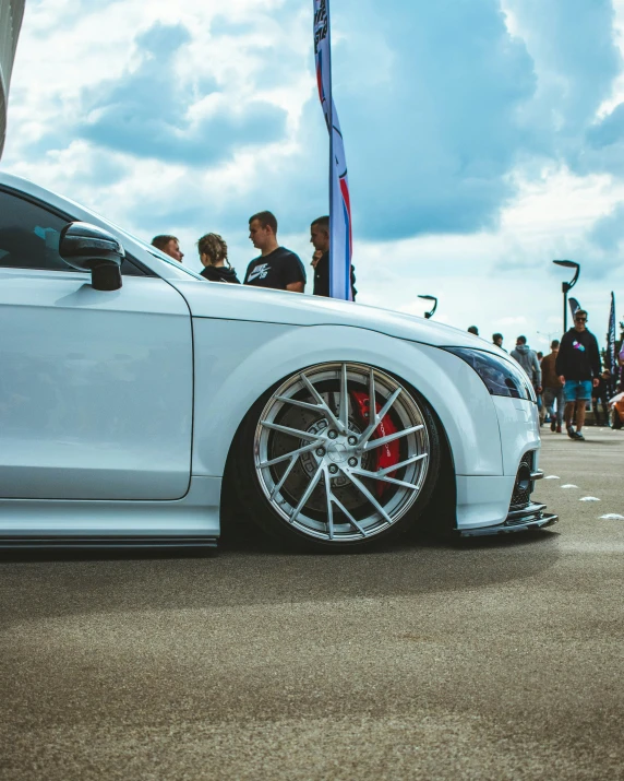 an automobile parked at a car show with lots of people