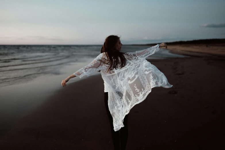 a woman stands on the beach and looks out at the ocean