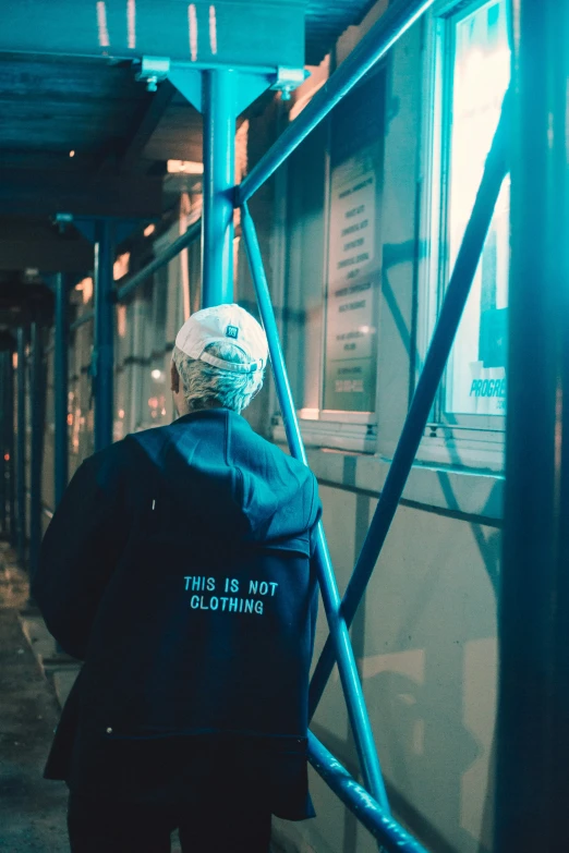 man walking down street by building with blue paint on the walls