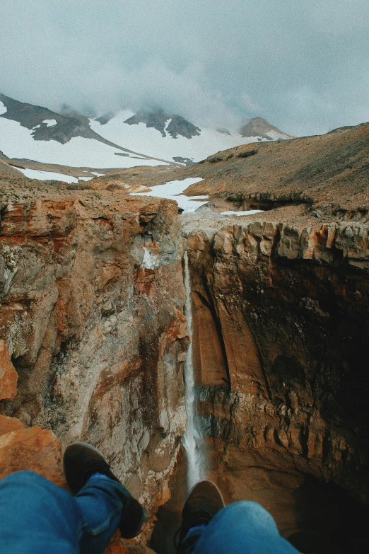 view from inside a helicopter of an aerial view of a man standing on a cliff