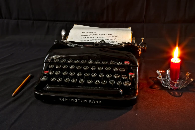 an old fashioned typewriter and a candle sit on a table