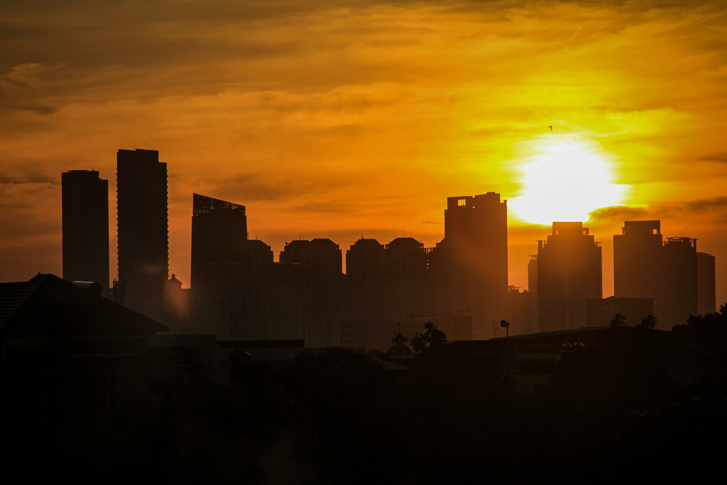 the sun sets behind some very large tall buildings