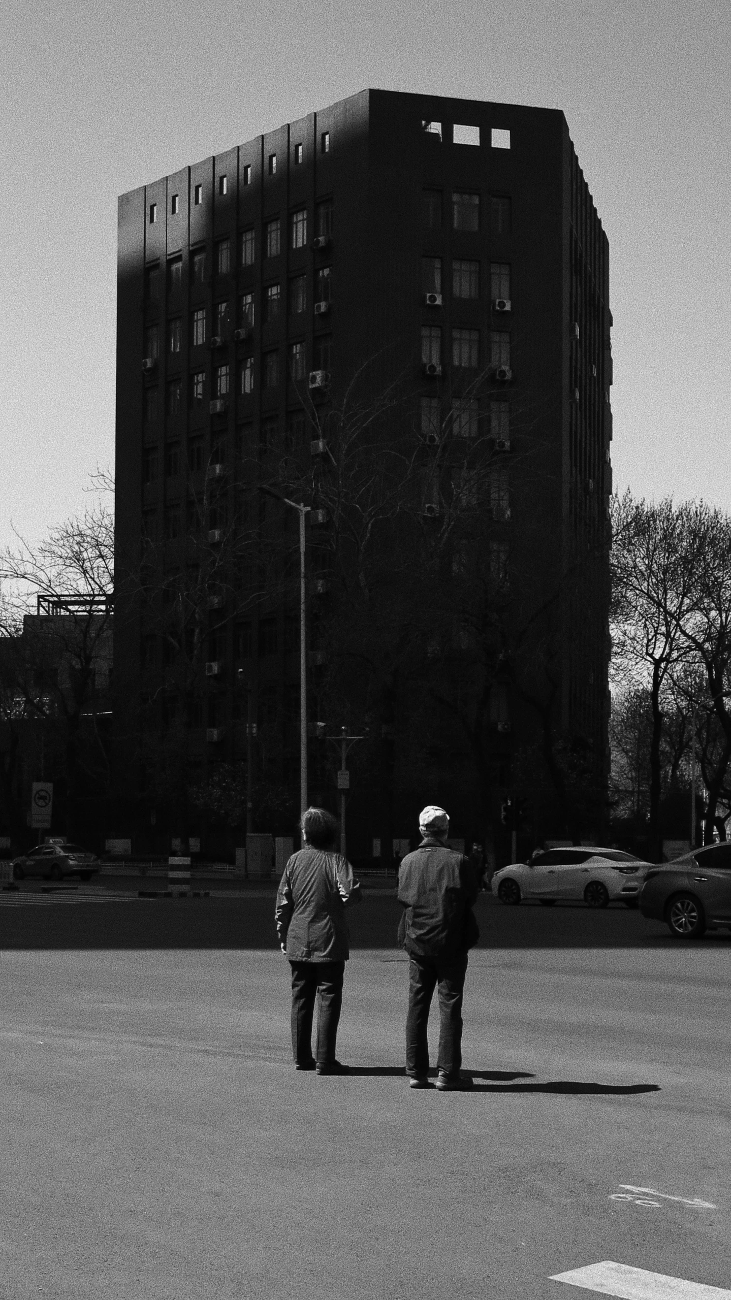 two people walking along the sidewalk of a city street