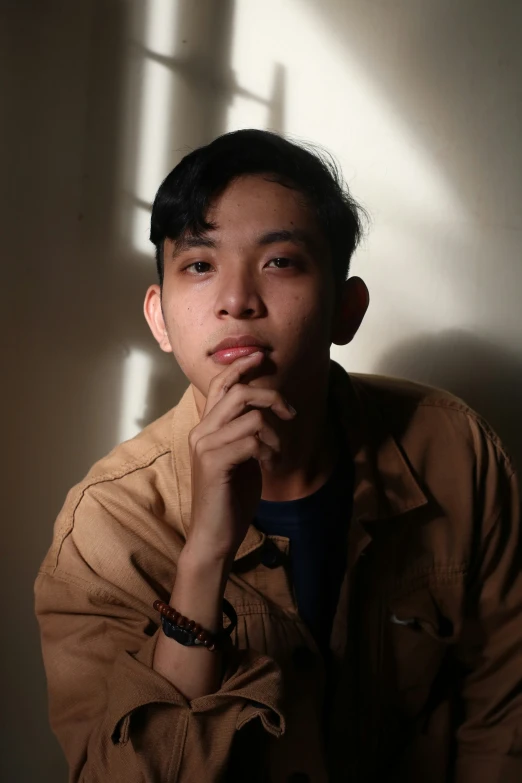 a man in tan shirt and white wall next to window