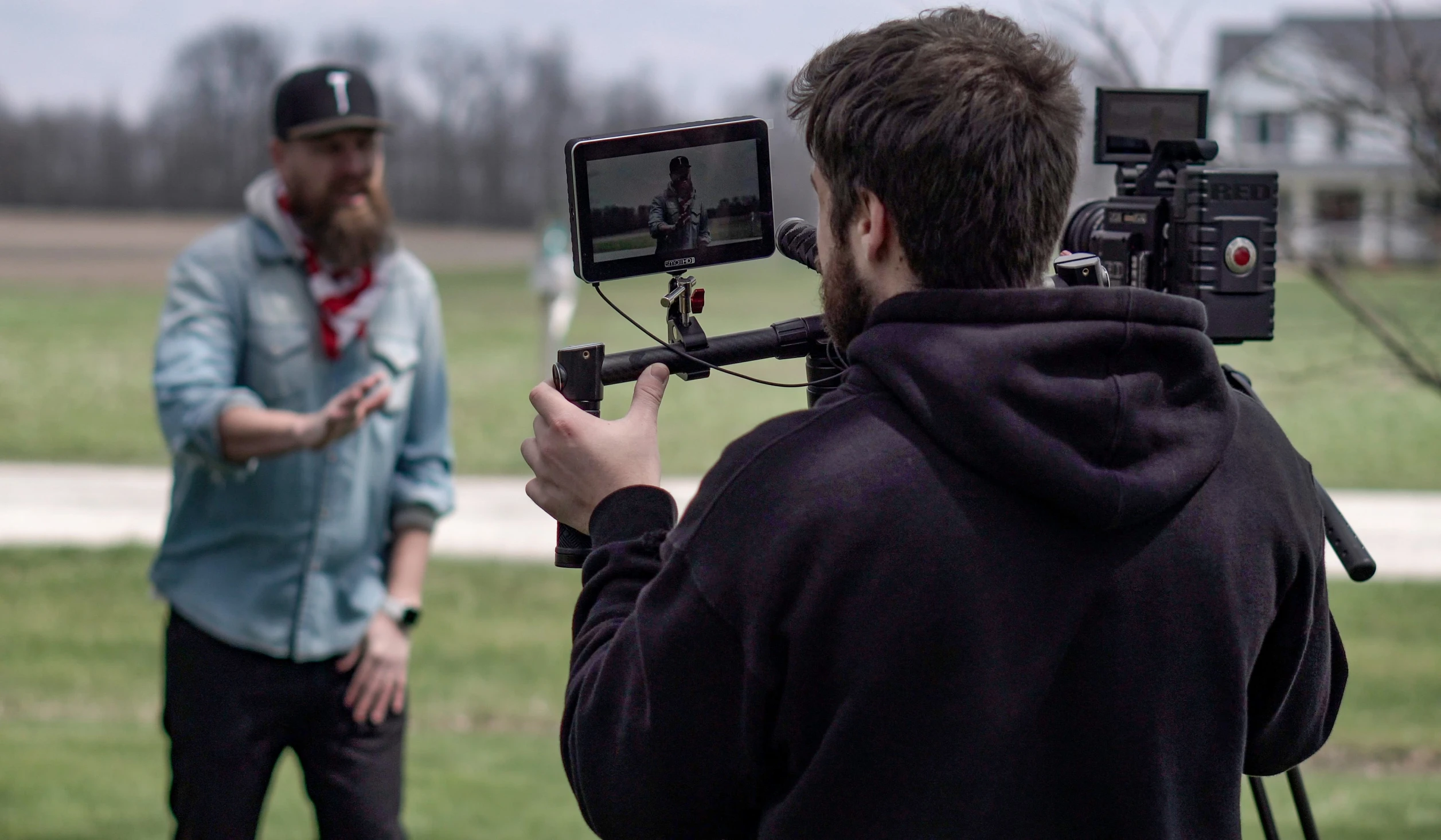 a man standing on the grass filming a tv