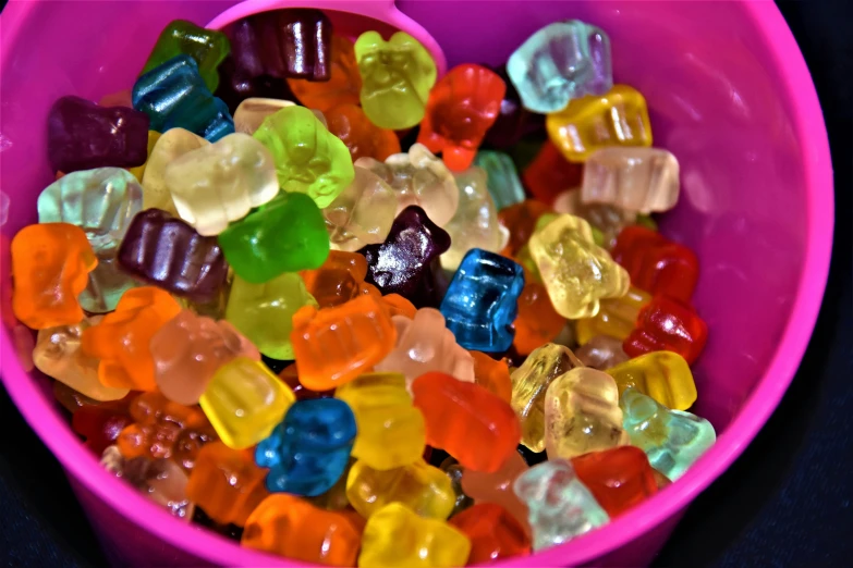 a pink bowl with jelly beans on a black table