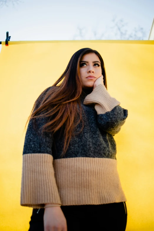 a woman with long hair posing in front of a yellow backdrop