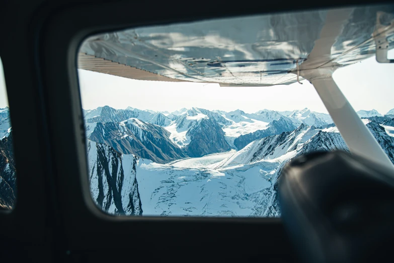 a view from the airplane looking down at a snowy mountain