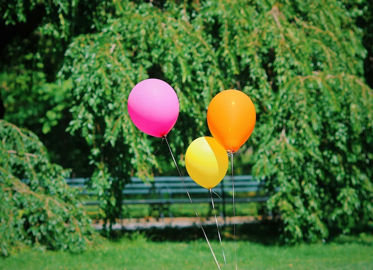 three balloons are being flown in front of a bench
