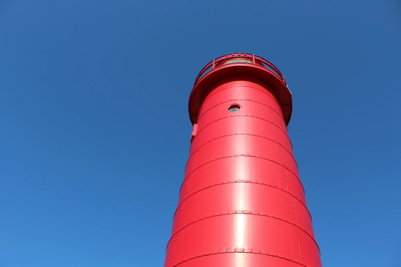 a large red lighthouse on top of a blue sky