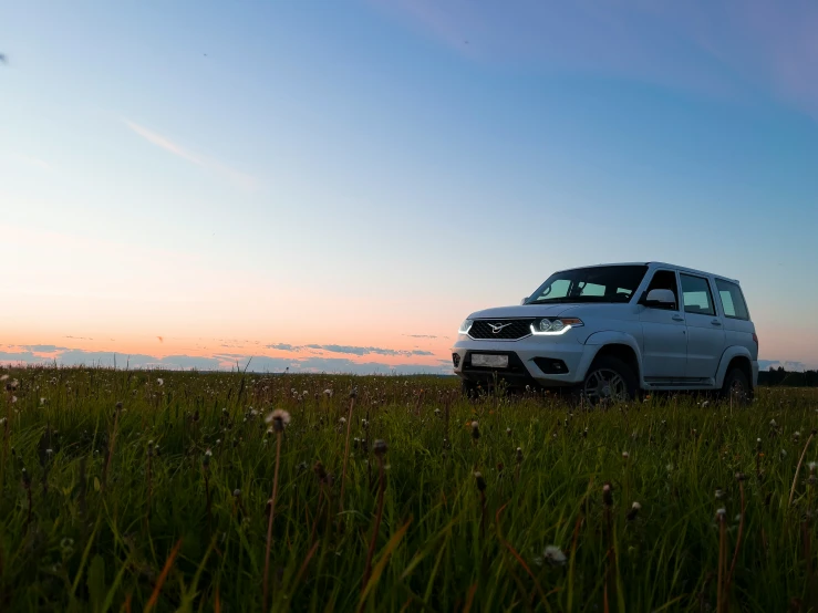 the front end of a small, four door suv on a field at sunset