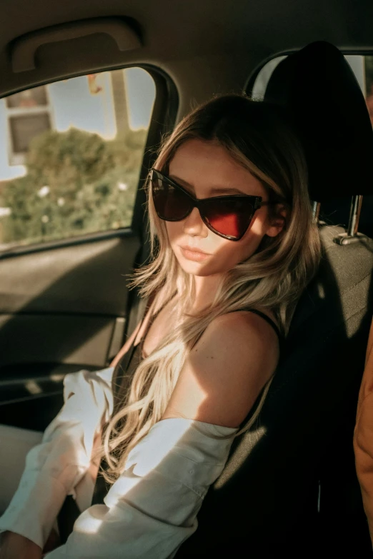 a beautiful young lady in a car wearing sunglasses