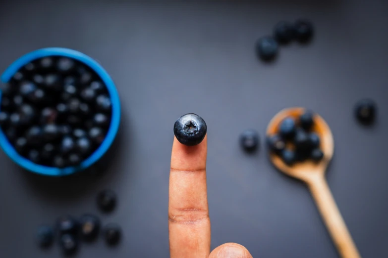 there is a person giving the peace sign with some berries in the background