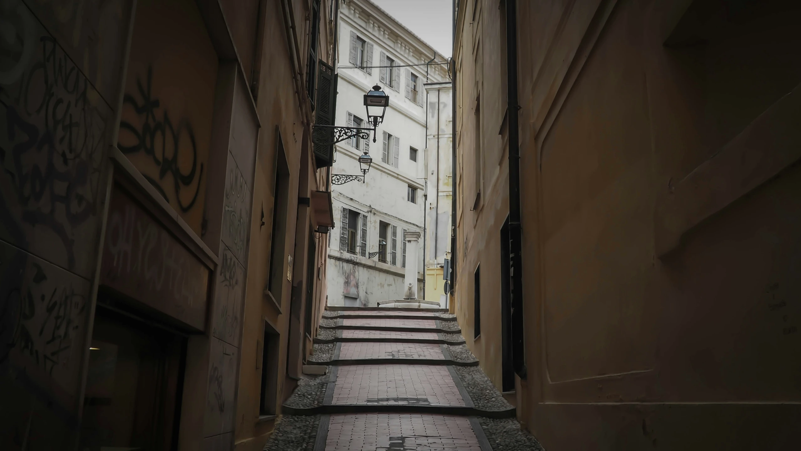 a narrow alleyway has graffiti on the buildings