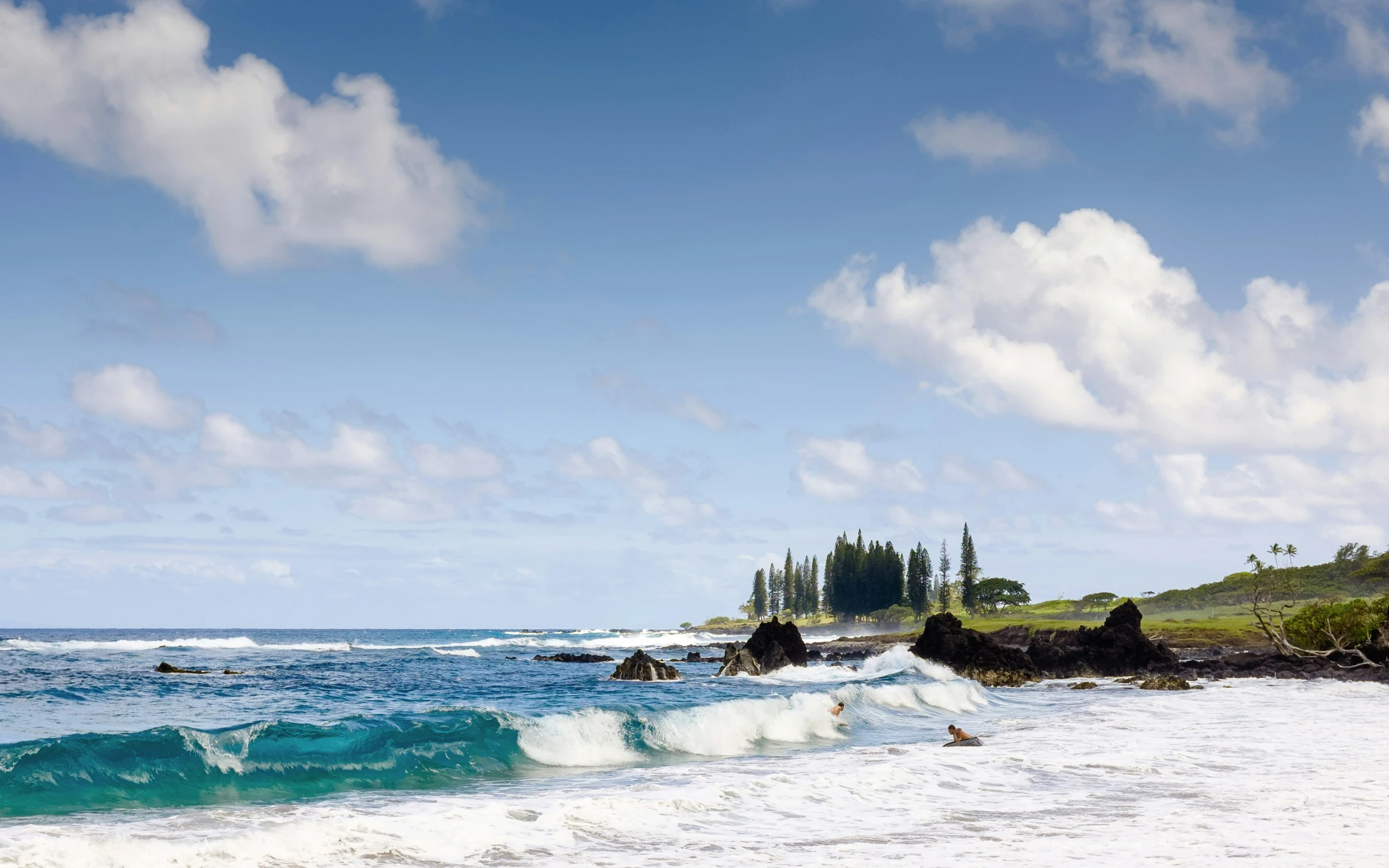 waves crash into a sandy beach in front of an island