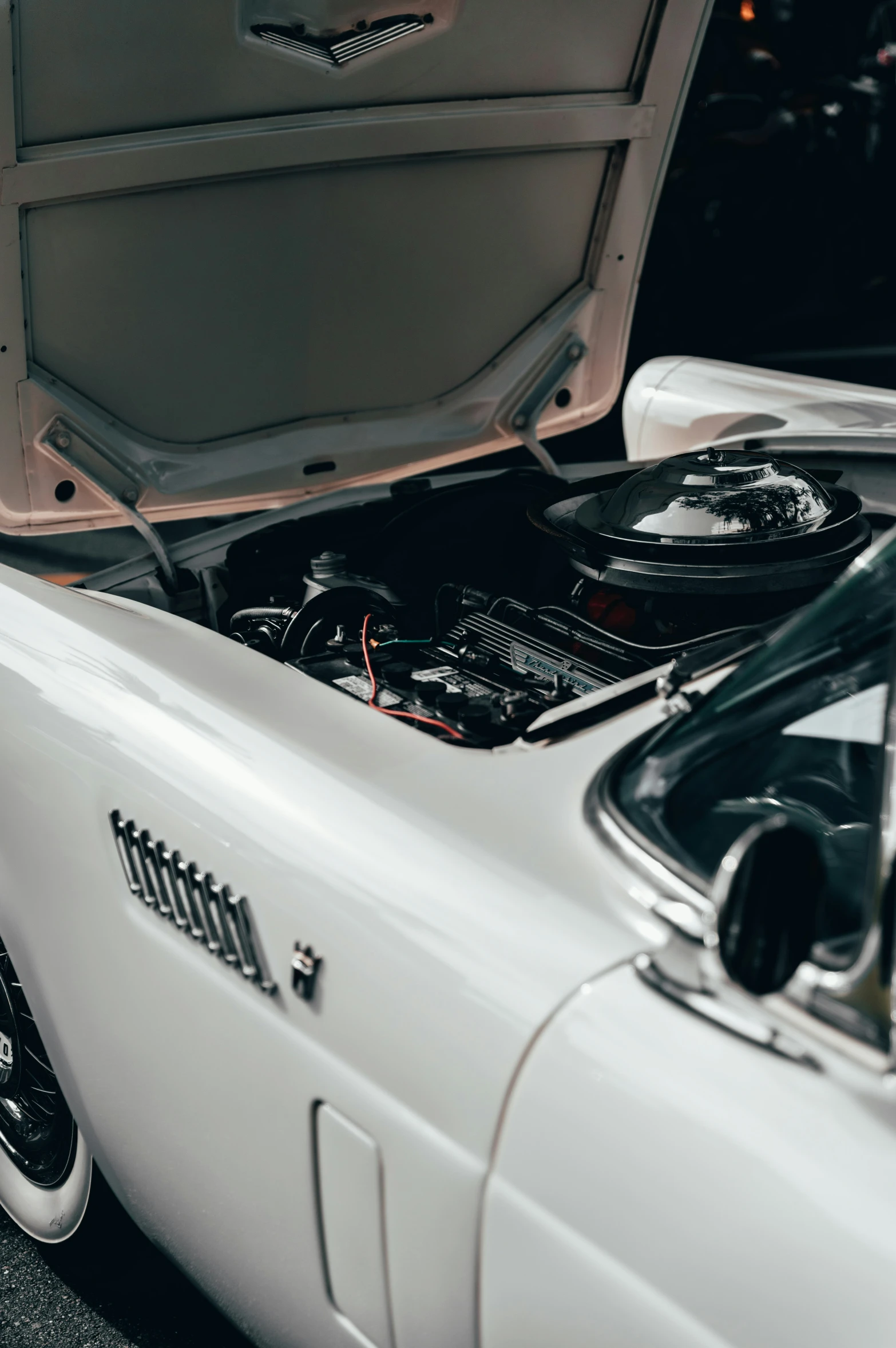 a white car has its hood up and there are electronic equipment underneath it