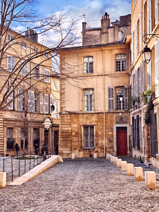 a group of buildings with cobblestones on one side and two sets of doors to the other