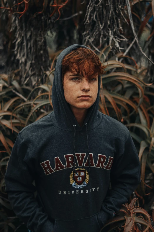 a man standing next to some bushes wearing a hoodie