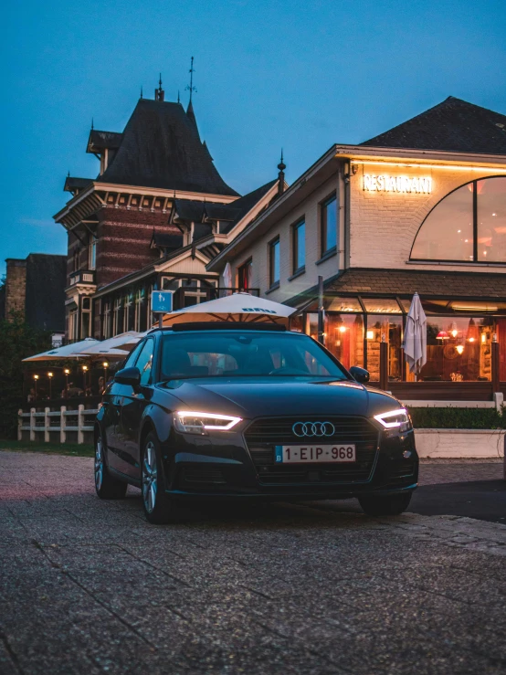 a car is parked on a cobblestone road in front of a restaurant