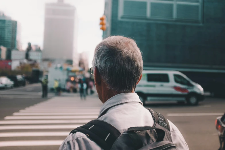 an elderly man with gray hair standing on a sidewalk