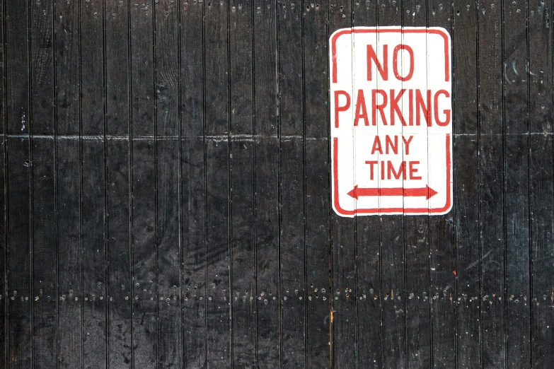 a sign on the back of a black fence stating no parking any time