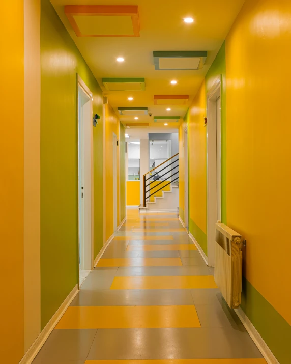 a long hallway is painted yellow and green with geometric designs