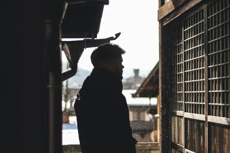 man standing in an alley while looking out at the rain