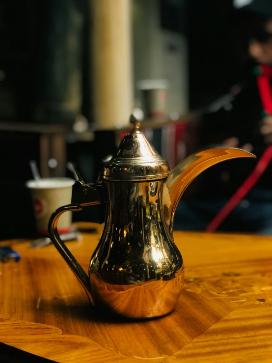 a gold teapot sitting on top of a wooden table
