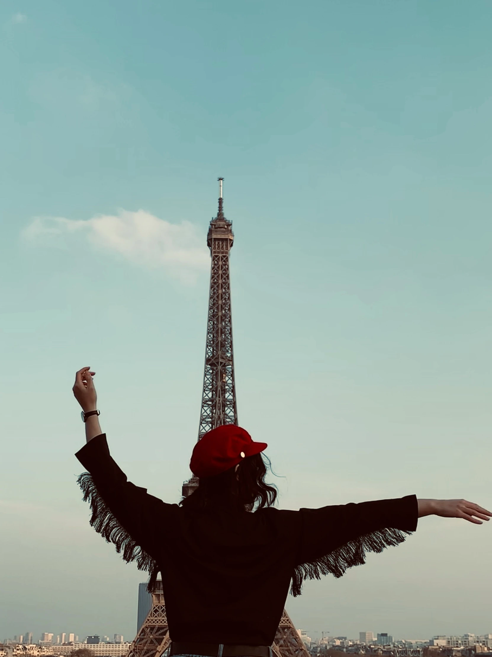 a woman with arms wide open in front of the eiffel tower