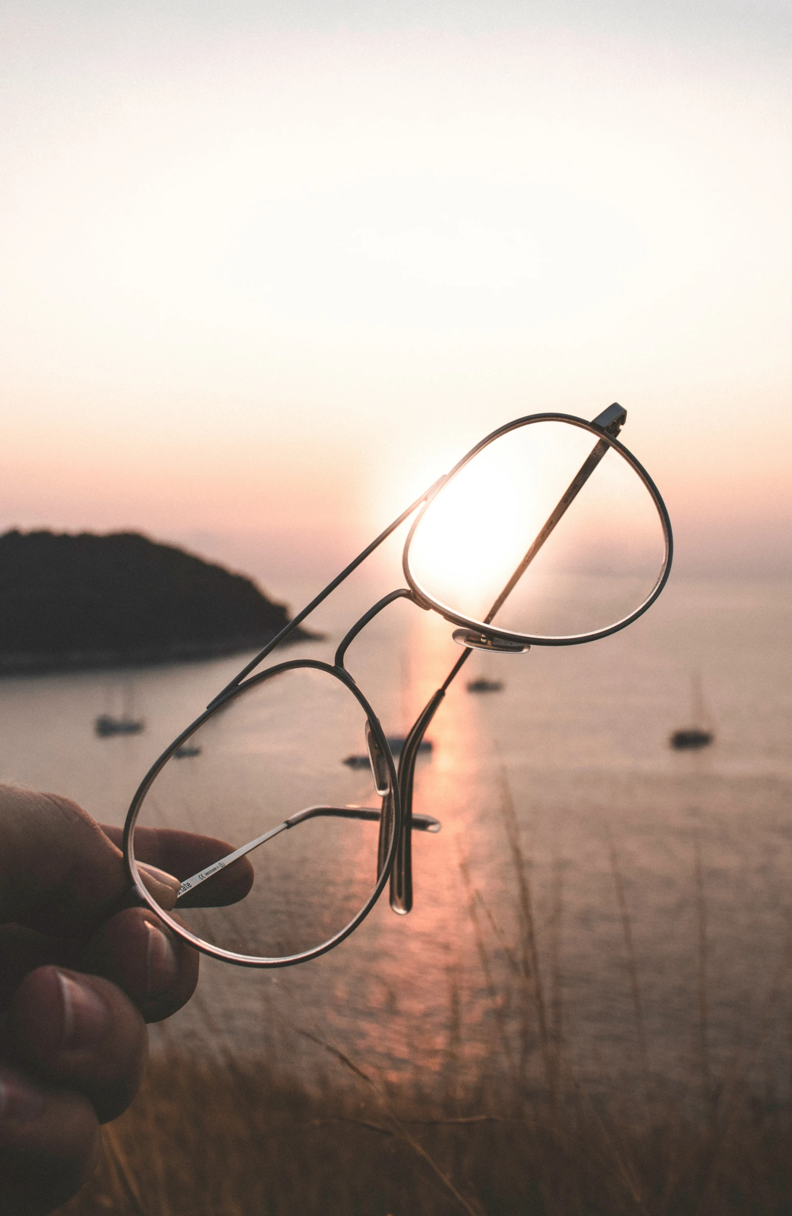 the sun sets over the ocean and reflects in a pair of glasses