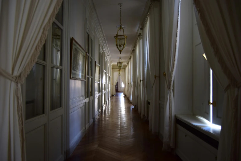 a person walks down an hallway lined with curtains