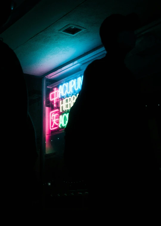 a man is silhouetted against the neon sign