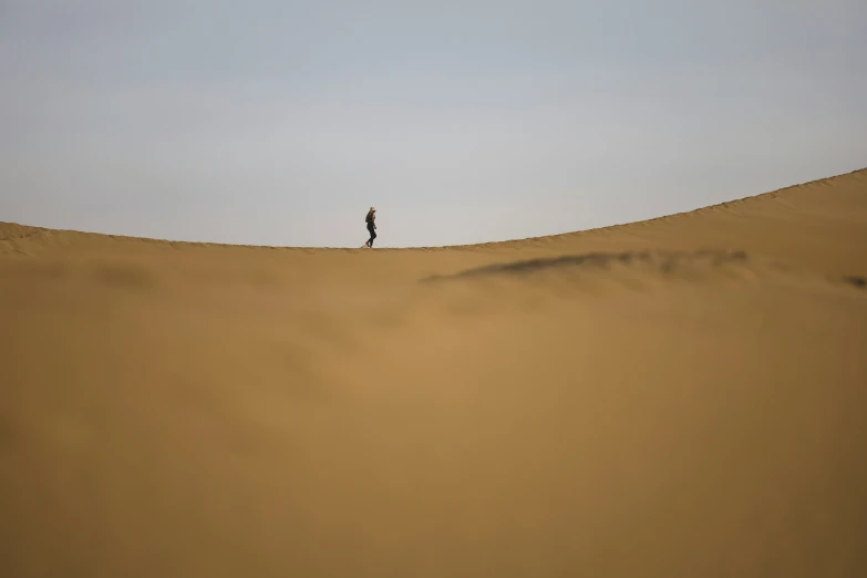 lone person on a wide dune in the desert