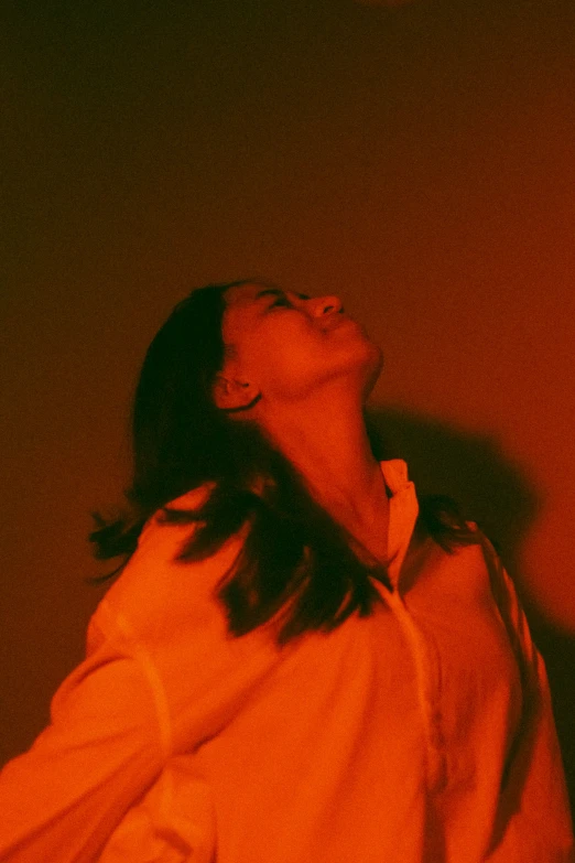 a young lady in an orange background looking upward