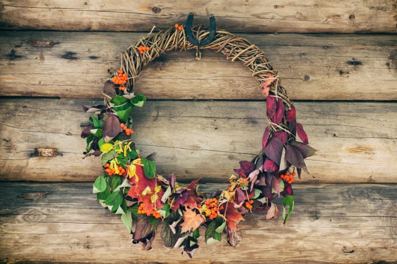 colorful wreath of dry leaves sits on a wood wall