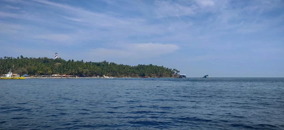 boat on a large body of water in front of an island with a light house