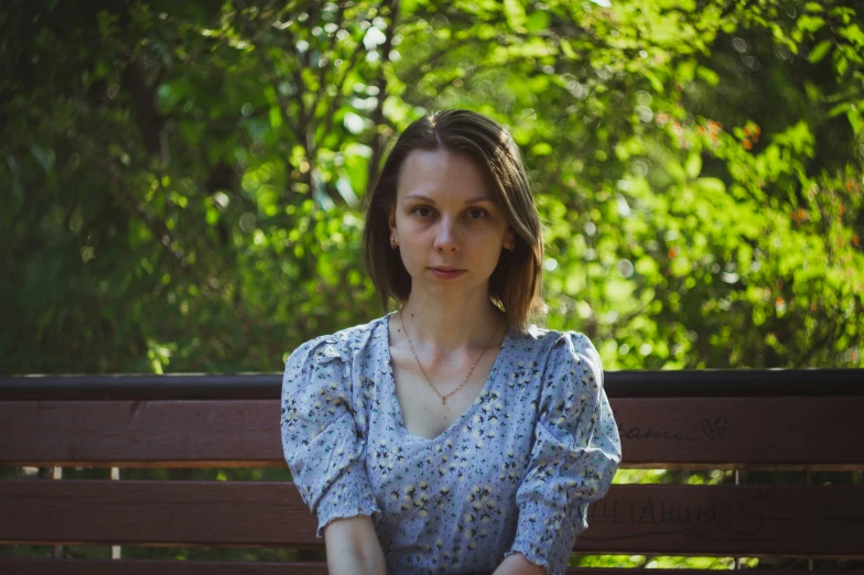 a woman is sitting on a bench in a park