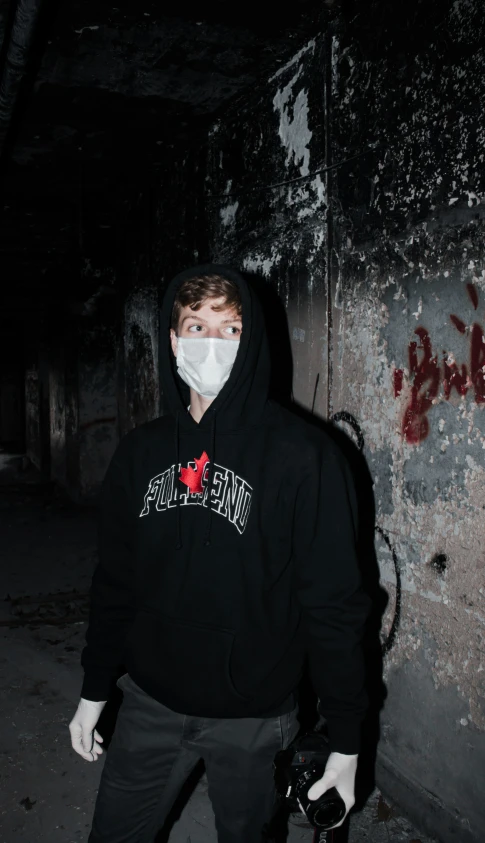 a man wearing a mask in the dark with graffiti