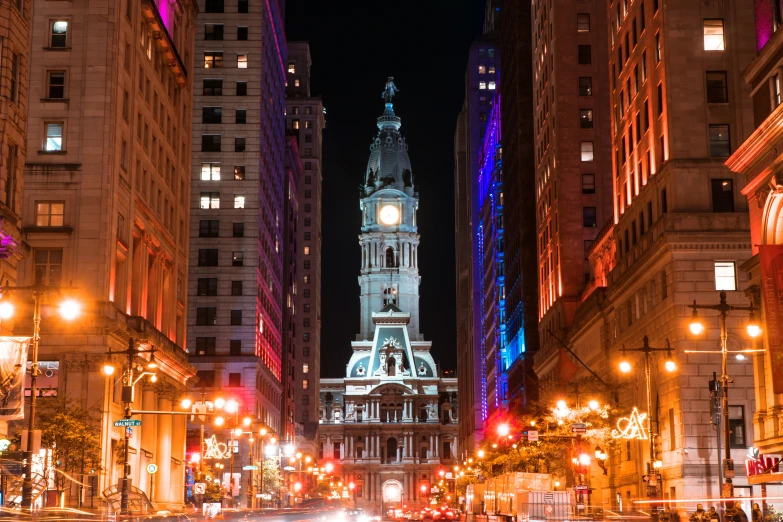 a city street at night with tall buildings in the background