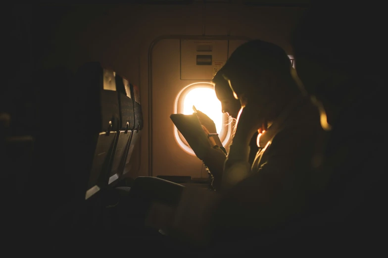 a man is looking at the phone beside an airplane window