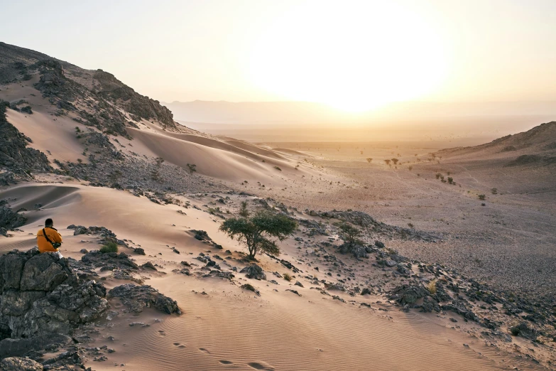 a man is sitting on top of the sand dunes