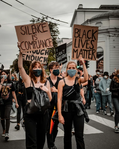 people with masks holding signs protesting a strike against complaced black lives matter