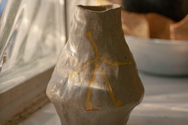 a clay vase sitting next to a white bowl