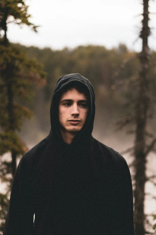 man standing in front of a forest with trees