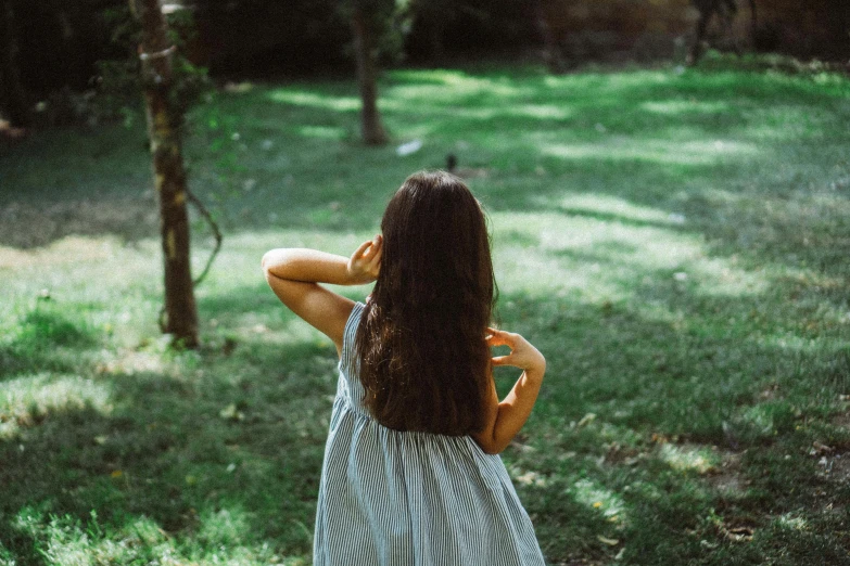 back view of a young woman in striped dress holding her hair up