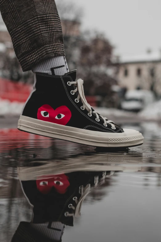 a person wearing black and white shoes with red heart eyes