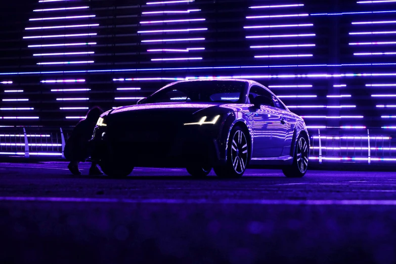 a black and white car in front of neon lights