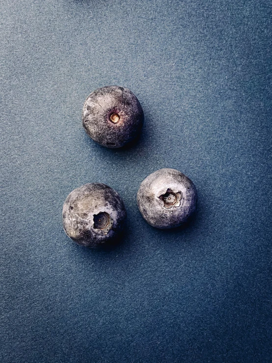 three blueberries sitting on top of a black surface